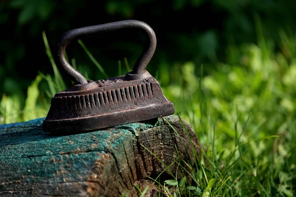 Vintage rusty iron on the green grass background closeup taken.Decoration aged things. Vintage things for home. Craft souvenirs for home and garden.