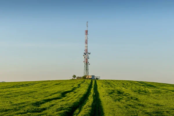 丘の上の畑の風景の中の丘の上に横たわる放送塔の眺め — ストック写真