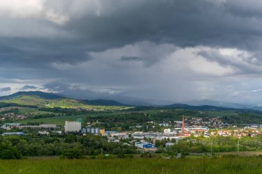 Valasske Mezirici kasabasının manzarası. Ufuktaki tepelerde yağmur sırasında güneş manzaraya doğru parlıyor..