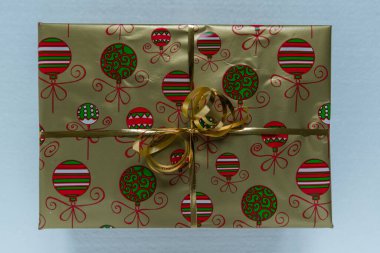 Altın folyo ve kağıtla paketlenmiş Noel hediyesinin köşesinden yakın plan görüntüsü. Üzerinde Xmas motifleri ve kurdelesi var..