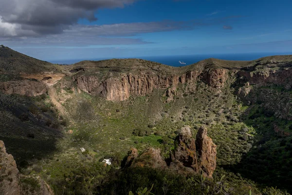 View of the mountainous landscape of volcanic origin along with lots of trees and vegetation and on the horizon, you can see the setting moon Gran Canary island