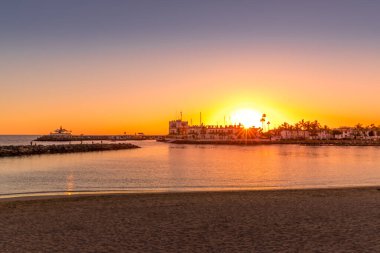 Ufuktaki turuncu kırmızı bulutların üzerinde gün batımı ve kentsel alanla deniz seviyesine yansıyan ışıkların yansımaları Büyük Kanarya Adası Valle