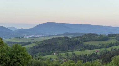 Karanlık bir günbatımının zamanlaması dağlara ve tepelere bakıyor tepenin altında uzanan Zubri kasabasına güneş batarken kasaba yavaşça aydınlanıyor..