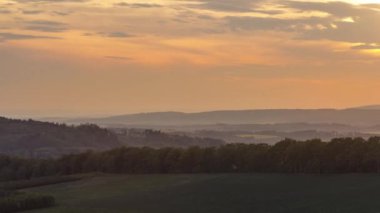 Gün batımında hareket eden bulutlarla Beskydy Çek Cumhuriyeti ulusal parkı üzerindeki ormanların ve tepelerin üzerindeki turuncu bulutların zamanı..