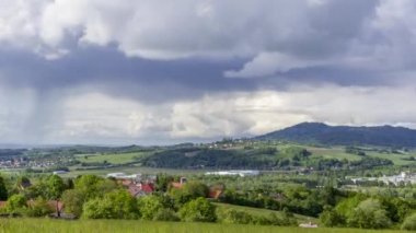 Günbatımının zamanlaması turuncu tepelerle dolu dağlık bir arazide yağışlı bir sabah Hranice na Morave Çek Cumhuriyeti boyunca uzanan kasaba ve evlerin manzarasını değiştiriyor.