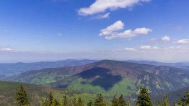 Dağ tepelerinin zamanı ve etrafındaki dağlık arazi beyaz bulutların şekil değiştirdiği ve çevresindeki tepelerin gölgesi gibi yansıttığı Lysa dağının manzarası..