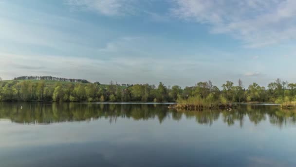 Jour Timelapse d'un lac sur lequel les nuages se déplacent avec réflexion sur la surface de l'eau pendant l'après-midi avec vue sur les collines et les montagnes de la région morave près de la ville de Hustopece