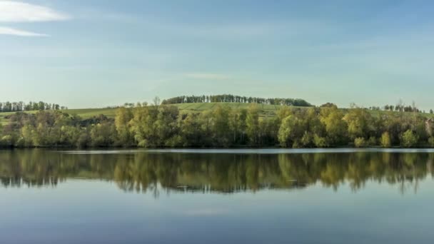 Déplacement latéral Timelapse de la surface calme du lac avec vue sur la campagne environnante pleine de collines stomas lors d'une journée ensoleillée nuages blancs dans le ciel réfléchissant sur la surface de l'eau Hustopece République tchèque