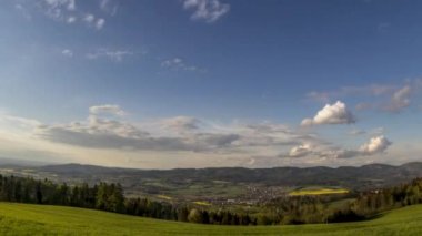 Gün batımında çekim hızını aşan çekim alanı bulutları bulutları yansıtıyor. Dağların aşağısındaki köyü gören bulutlar. Orada tarlalar ve evler var Beskydy Zasova köyü.