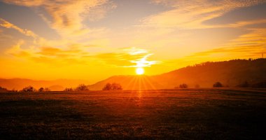 Velka Lhota zirvesinde gün batımı gölgeler ve güneş parkları turuncu günbatımında sonbahar tepelerinde gölgede yakalanır..