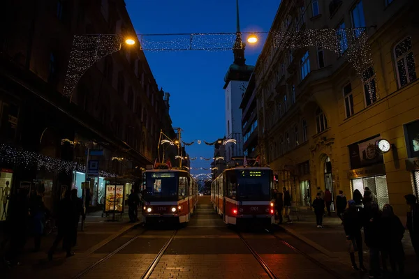 公共交通機関は2つあり クリスマスが始まる前の日没時にチェコのブルノのスボディ広場で撮影された路面電車が市内に点灯します — ストック写真