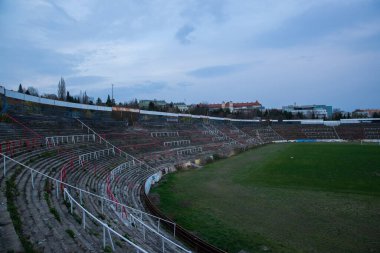 Abadoned Stadion Za Luzankami, Çek Cumhuriyeti 'nin Brno kentinde aktif olmayan bir stadyumdur. Bahar günbatımında yakalanan gökyüzü ve bulutlar mavi ve koyu renklere boyanmıştı. Fotoğraf Tribünlerden ve alanın ortasından..