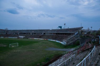 Abadoned Stadion Za Luzankami, Çek Cumhuriyeti 'nin Brno kentinde aktif olmayan bir stadyumdur. Bahar günbatımında yakalanan gökyüzü ve bulutlar mavi ve koyu renklere boyanmıştı. Fotoğraf Tribünlerden ve alanın ortasından..