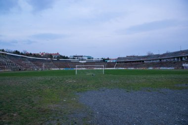 Abadoned Stadion Za Luzankami, Çek Cumhuriyeti 'nin Brno kentinde aktif olmayan bir stadyumdur. Bahar günbatımında yakalanan gökyüzü ve bulutlar mavi ve koyu renklere boyanmıştı. Fotoğraf Tribünlerden ve alanın ortasından..