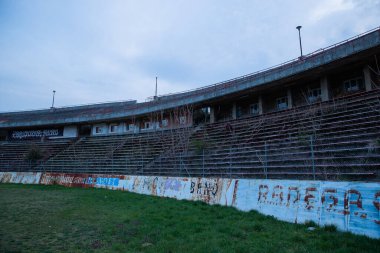 Abadoned Stadion Za Luzankami, Çek Cumhuriyeti 'nin Brno kentinde aktif olmayan bir stadyumdur. Bahar günbatımında yakalanan gökyüzü ve bulutlar mavi ve koyu renklere boyanmıştı. Fotoğraf Tribünlerden ve alanın ortasından..