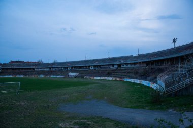 Abadoned Stadion Za Luzankami, Çek Cumhuriyeti 'nin Brno kentinde aktif olmayan bir stadyumdur. Bahar günbatımında yakalanan gökyüzü ve bulutlar mavi ve koyu renklere boyanmıştı. Fotoğraf Tribünlerden ve alanın ortasından..