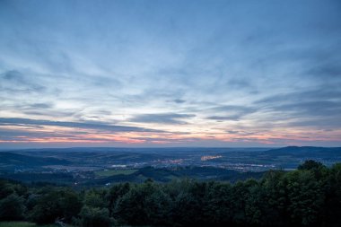 Şehir ve çevresindeki Valasske Mezirici kasabasının üzerindeki batan günbatımı kamuoyu yavaş yavaş çok renkli kara bulutları ve ufukta gizlenen güneşi aydınlatıyor..