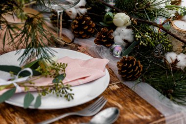 Çiçeklerle dolu eski ahşap bir düğün masası ve yiyecek için hazırlanmış bir yer. Kışın, ormanın ortasında, karla kaplı bir düğün merasimi.