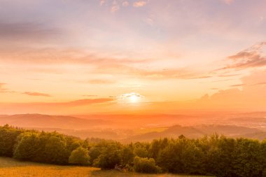 Gün batımında manzara tamamen renkli bulutlar turuncu ve mor ve arkasında güneş ve yaz sonu çekilen Valasske Mezirici şehri..