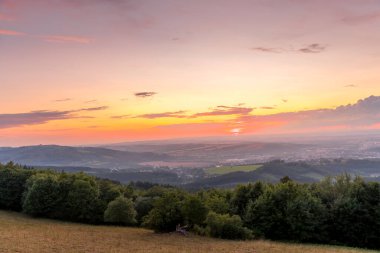 Gün batımında manzara tamamen renkli bulutlar turuncu ve mor ve arkasında güneş ve yaz sonu çekilen Valasske Mezirici şehri..