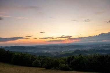 Gün batımında manzara tamamen renkli bulutlar turuncu ve mor ve arkasında güneş ve yaz sonu çekilen Valasske Mezirici şehri..