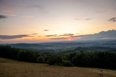 Gün batımında manzara tamamen renkli bulutlar turuncu ve mor ve arkasında güneş ve yaz sonu çekilen Valasske Mezirici şehri..