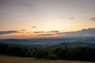 Yazın geç saatlerde Valasske Mezirici 'nin yakaladığı mavi gökyüzü ve ormana sahip çayır manzarası..