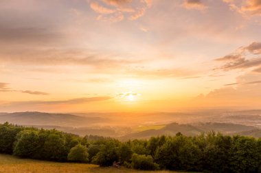 Yazın geç saatlerde Valasske Mezirici 'nin yakaladığı mavi gökyüzü ve ormana sahip çayır manzarası..
