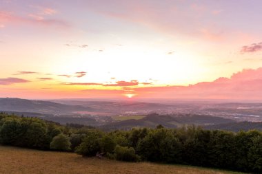 Gün batımında tamamen renkli bulutlar ve turuncu güneş batıyor ve Valasske Mezirici şehri yaz sonunda ele geçirildi.