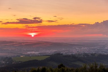 Gün batımında tamamen renkli bulutlar ve turuncu güneş batıyor ve Valasske Mezirici şehri yaz sonunda ele geçirildi.