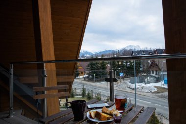 Dairenin balkonunda sabah kahvaltısı. Kış mevsiminde, dağ manzaralı.