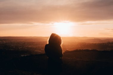 Şehir içi manzaralı taş ocağında gün batımında fotoğraf çeken bir kız. 