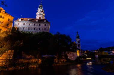 Günbatımında ünlü Cesky Krumlov Şatosu ile birlikte tarihi Cesky Krumlov şehrinin panoramik manzara manzarası, güzel gökyüzü ve bulutlarla kaplanmış UNESCO Dünya Mirası Bölgesi üzerindedir.