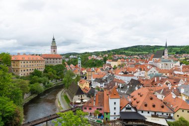 Kilisenin ünlü Cesky Krumlov Şatosu 'nun bulunduğu tarihi Cesky Krumlov şehrinin yukarıdaki panoramik manzara manzarası, ilkbaharda güzel bir gökyüzü ve bulutlarla yakalanan UNESCO Dünya Mirası Alanında yer alıyor.