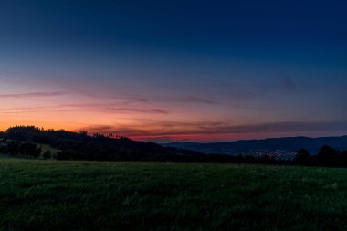 Tepenin çok renkli gökyüzü Velka Lhota Beskydy alan gökyüzü ve bulutlar gün batımında etrafındaki küçük tepeler ve dağları çevreleyen doğa alanını çevreleyen birçok renkle oynarlar..