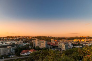 Brno şehrinde gün batımı turuncu gün batımında sergi merkezi ve bir tepede daireler ve halka açık ışıklar çevrimiçi oluyor.