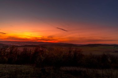 Gün batımından birkaç dakika önce Brno Hill 'den doğaya ve manzaraya tepeden bakan turuncu renkli bulutlar arka planda hareket ederken ve gökyüzünde uçan uçaklar....