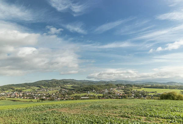 Moving clouds in two directions, above the village of the Krhova Beskydy Czech republic looking at horizon around with visible hills and mountains during sunny days and field for crop