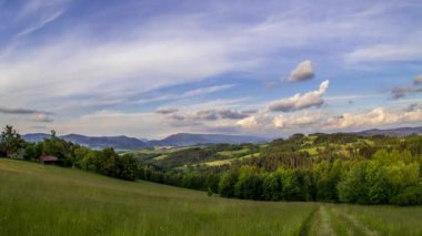 Çevresindeki ormanların ve vadideki bir köyün manzarasının olduğu doğal bir manzara. Beskydy Çek Cumhuriyeti 'nin dağlık arazisinde bulutlara doğru hareket eden bir kamera.