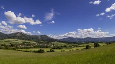 Güneşli bir günde Beskydy Dağları 'nın korunaklı bölgesinde bulunan ve Kozlovice köyünün gökyüzünde hızla hareket eden beyaz bulutları gören dağlık bir araziye doğru hareket eden zaman çizelgesi..