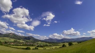 Beskydy Dağları 'nın eteklerindeki dağlık bir arazide güneşli bir günde Kozlovice köyünün gökyüzünde hızla hareket eden bulutlarını gösteren birçok tepenin olduğu geniş bir zaman çizelgesi..