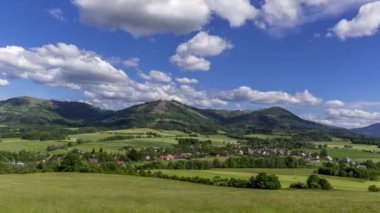 Beskydy Dağları 'nın korunan bir bölgesinde, güneşli bir günde Kozlovice köyünü ve gökyüzünde hızla hareket eden beyaz bulutları gören dağlık bir manzaranın zamanlaması..
