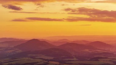 Beskydy Dağları üzerinde turuncu-altın bir gün batımının zamanı ve çevresindeki köyler bir vadide uzanır. Gökyüzünde altın bulutlar hareket eder ve güneş yan tarafta batar..