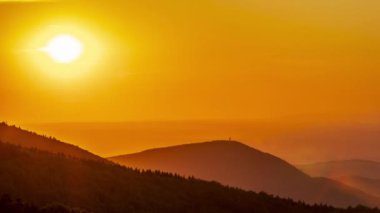 Gün batımında, güneşin sarıdan kırmızıya dönüşürken detaylı görüntüsü Beskydy Tepeleri 'nin dağlık alanının ve çevresini çevreleyen doğanın ardında yavaşça batar..