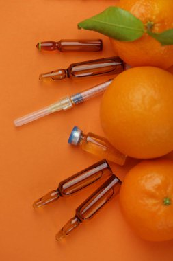 C vitamini enjeksiyonu. Şırıngalar, kahverengi cam ampuller ve taze narenciye meyveleri. 