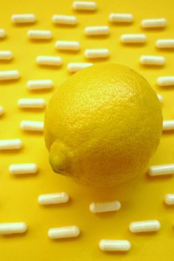 C vitamini konsepti. Sarı arka planda limon turunçgil ve tıbbi kapsüller.