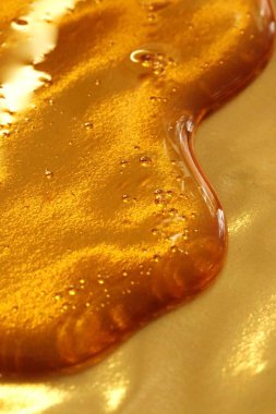 Altın bir arka planda bal damlıyor. Bal dokusu