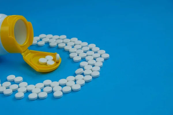 Weiße Pillen Einer Medizinflasche Mit Gelbem Deckel Auf Blauem Hintergrund — Stockfoto