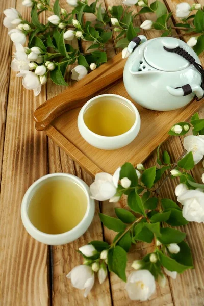 Jasmine tea. Organic tea with jasmine extract. green teapot and cups in Asian style on a wooden tray