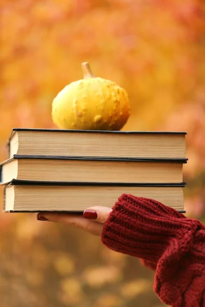 Autumn books reading.Stack of books and little yellow pumpkin